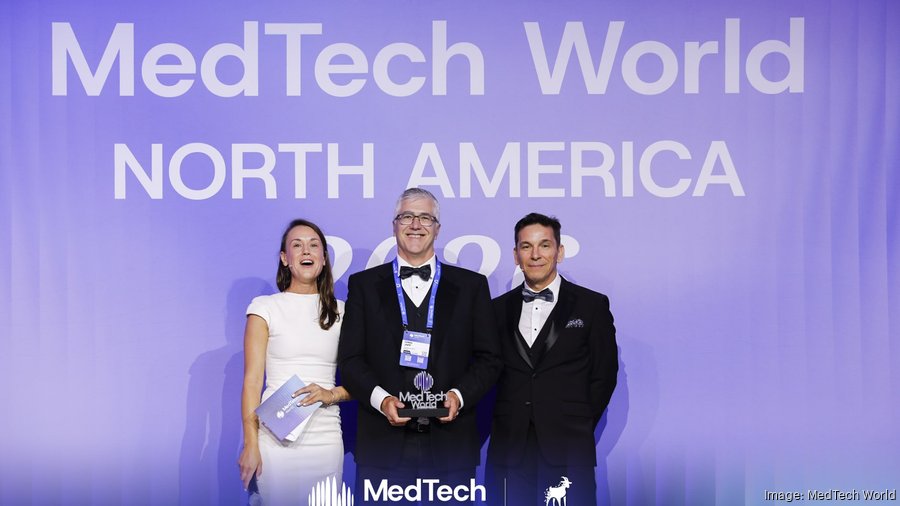 A woman and two men with an award